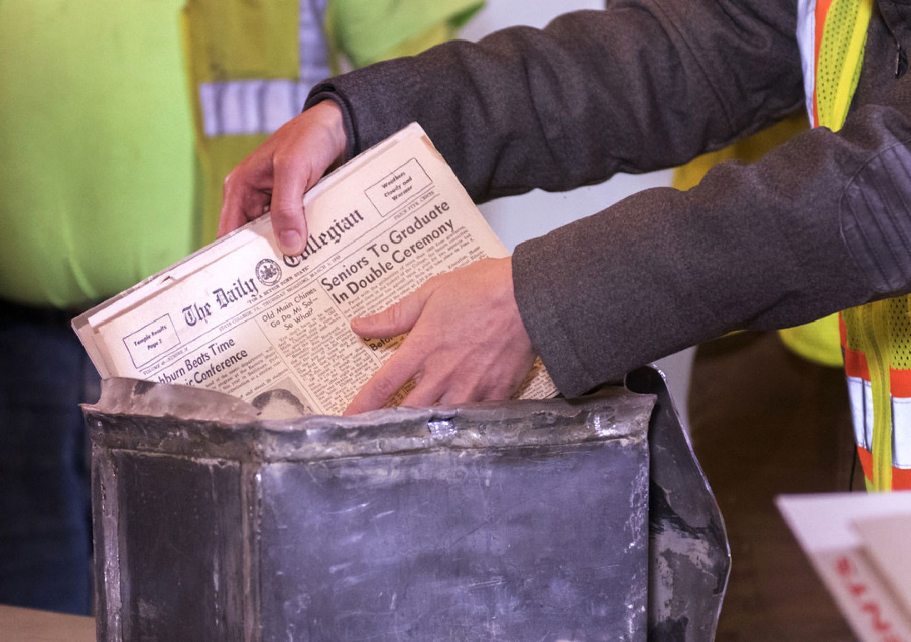 A newspaper is removed from a metal box that served as a time capsule.