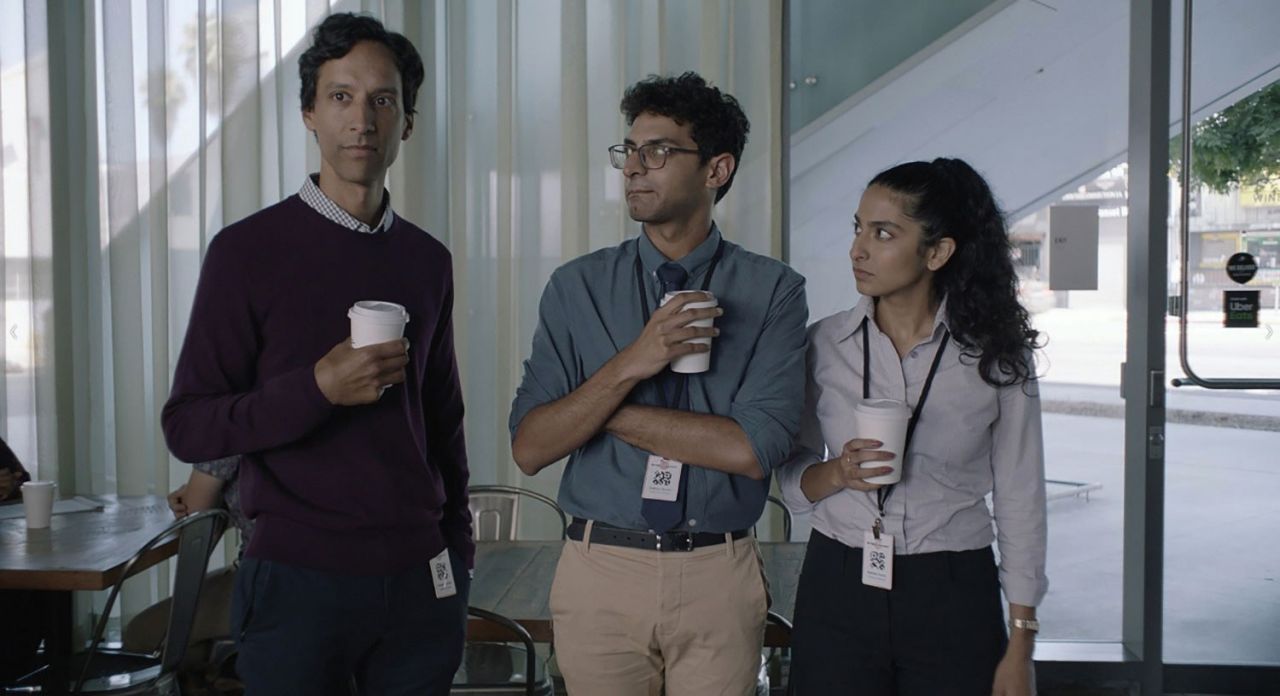 Three actors on the set of Coffee Shop Names hold white recyclable coffee cups.