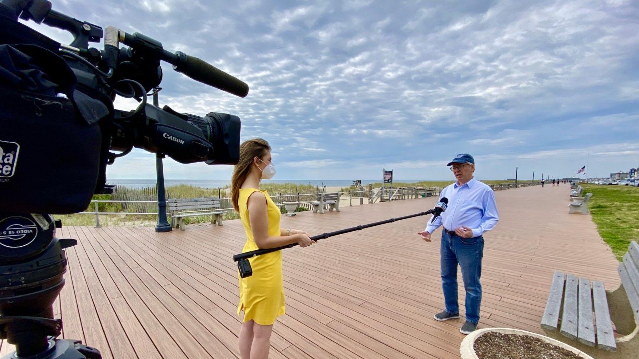 Alex Hogan uses a boom mic to conduct an interview on the boardwalk.