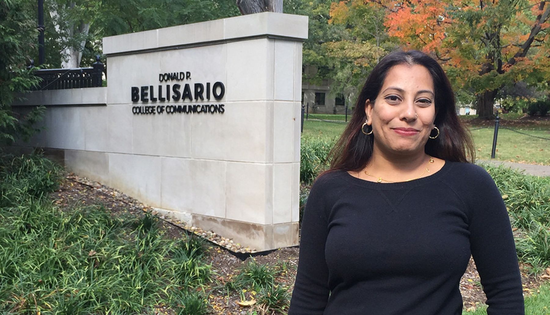 Shaheen Pasha stands on campus in front of a Bellisario College sign