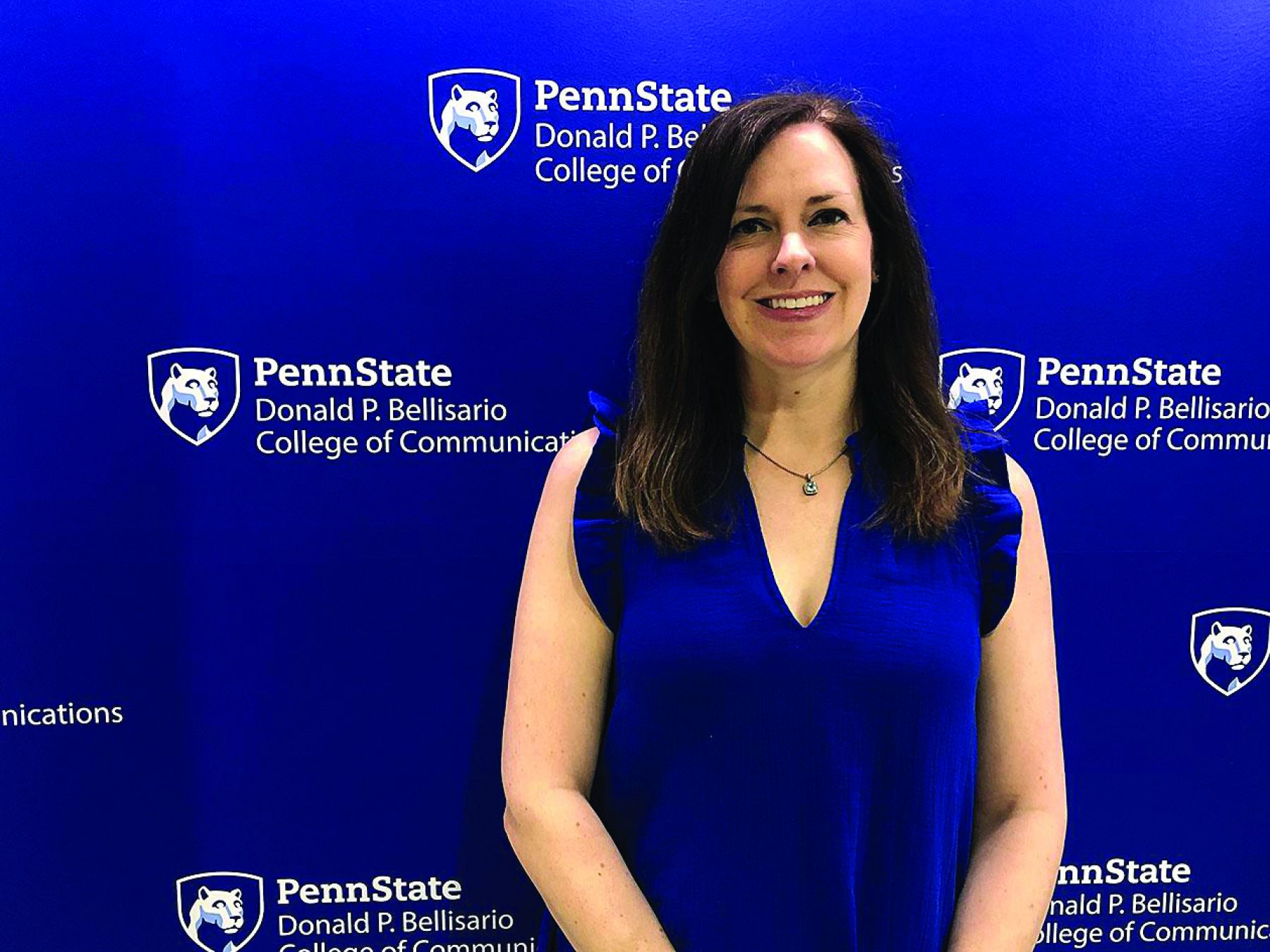 Dark haired woman standing in front of a blue wall