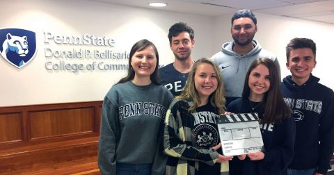 Six members of the spring class of the Penn State Hollywood Program pose in front of the Bellisario College logo
