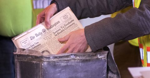 A newspaper is removed from a metal box that served as a time capsule.