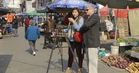 Tony Barbieri and a student on the street reporting with a camera in China.