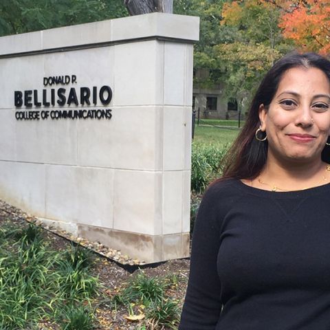 Shaheen Pasha stands on campus in front of a Bellisario College sign
