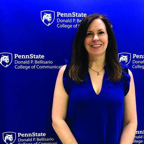 Dark haired woman standing in front of a blue wall